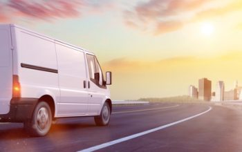 Van Lieferwagen mit Fracht macht einen Transport auf einer Straße zur Stadt